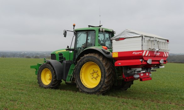 Fertiliser spreader and tractor in a field of winter wheat